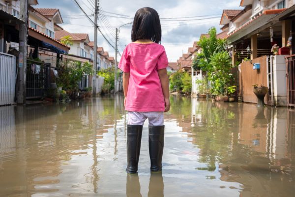 A girl standing in floodwaters on a villiage road