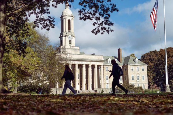 Students walk along a sidewalk in front of Penn State's Old Main building